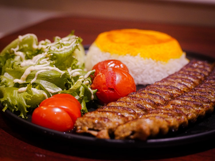 Assiette de grillade accompagnée de riz, salade et tomates.